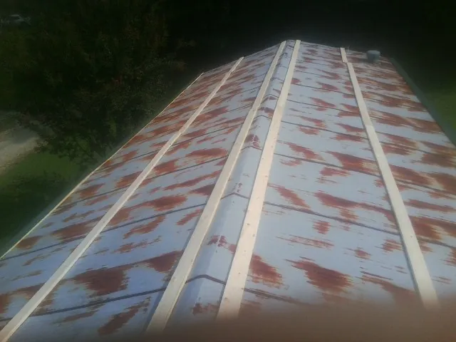 Rusted metal roof panels with new wood purlins before replacement — Storm Damage Roof Repair in Martensdale by Roofing Brothers