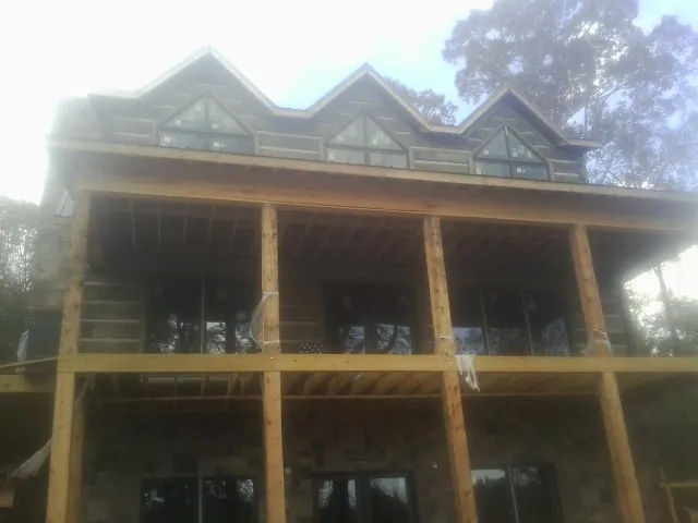 Dormers and porch framing on a large log home under construction — Roof Coating work by our crew in Martensdale