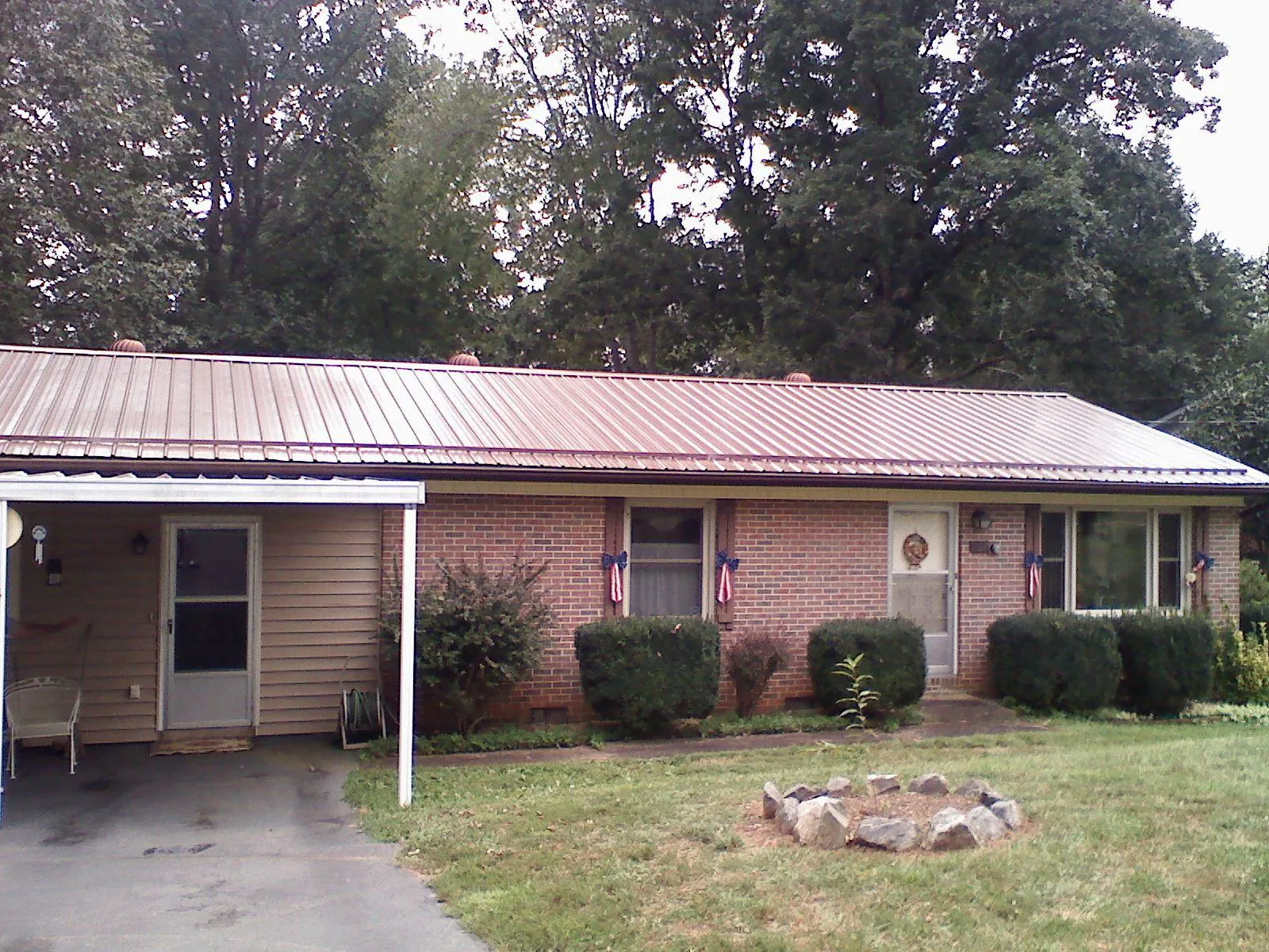 Bronze metal roof and carport on a brick ranch home — Roof Repair work by our crew in Martensdale