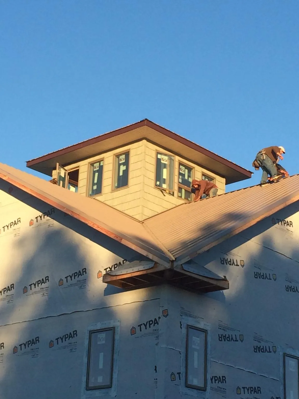 Roofers working around a rooftop cupola on a new metal roof at sunset — Roof Waterproofing in Martensdale by Roofing Brothers